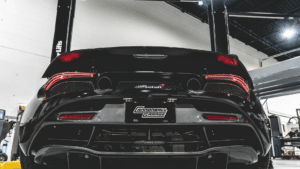 the rear end of a black sports car on a 2 post lift