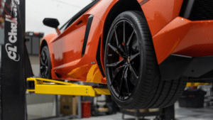 close up of orange sports car undergoing upgrades on Challenger's 2-post lift